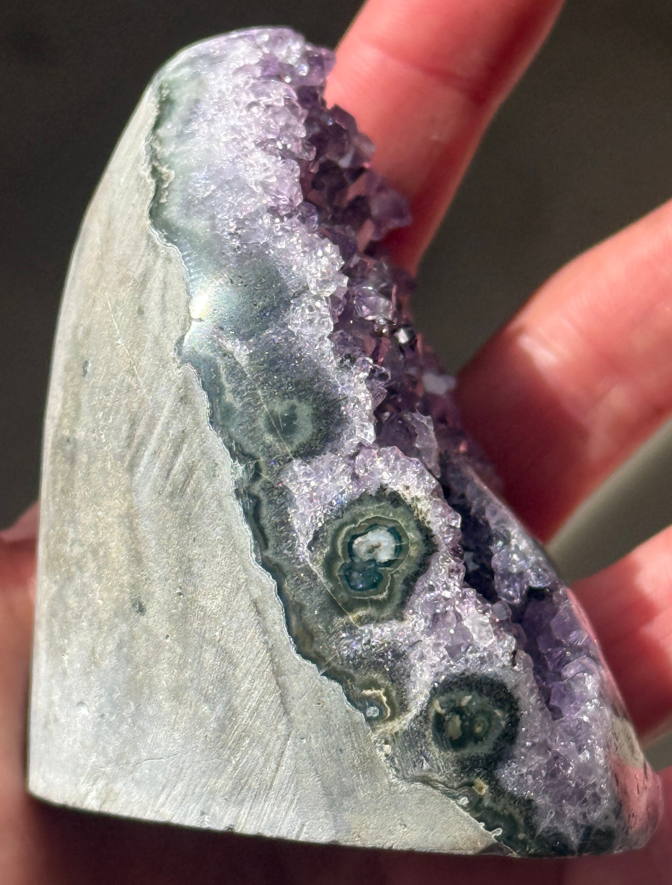 A polished amethyst geode, showcasing a rich purple hue with crystalline formations. The geode has a rounded top and a flat base, revealing the natural beauty of the gemstone.