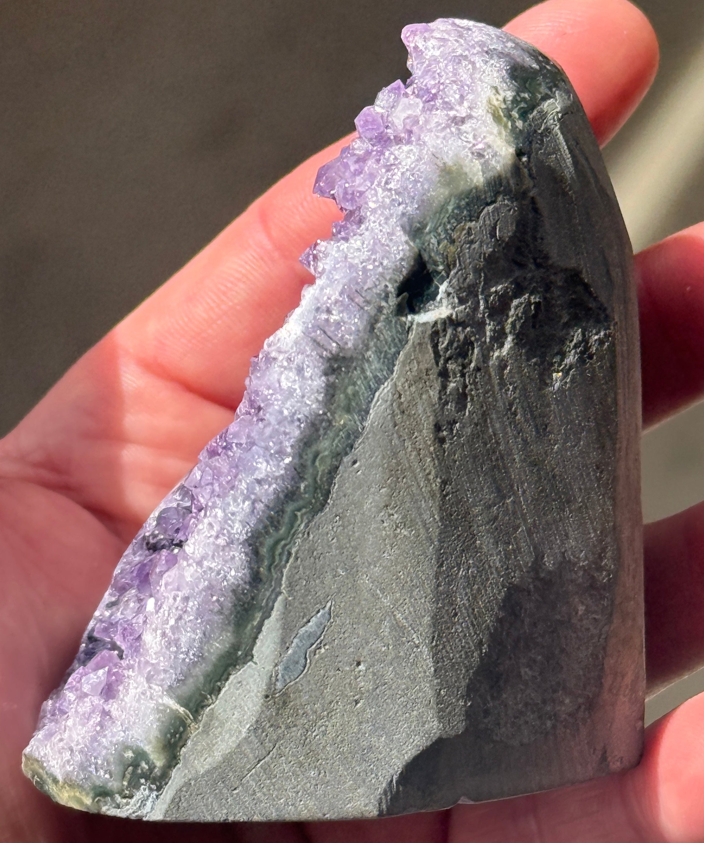 A polished amethyst geode, showcasing a rich purple hue with crystalline formations. The geode has a rounded top and a flat base, revealing the natural beauty of the gemstone.