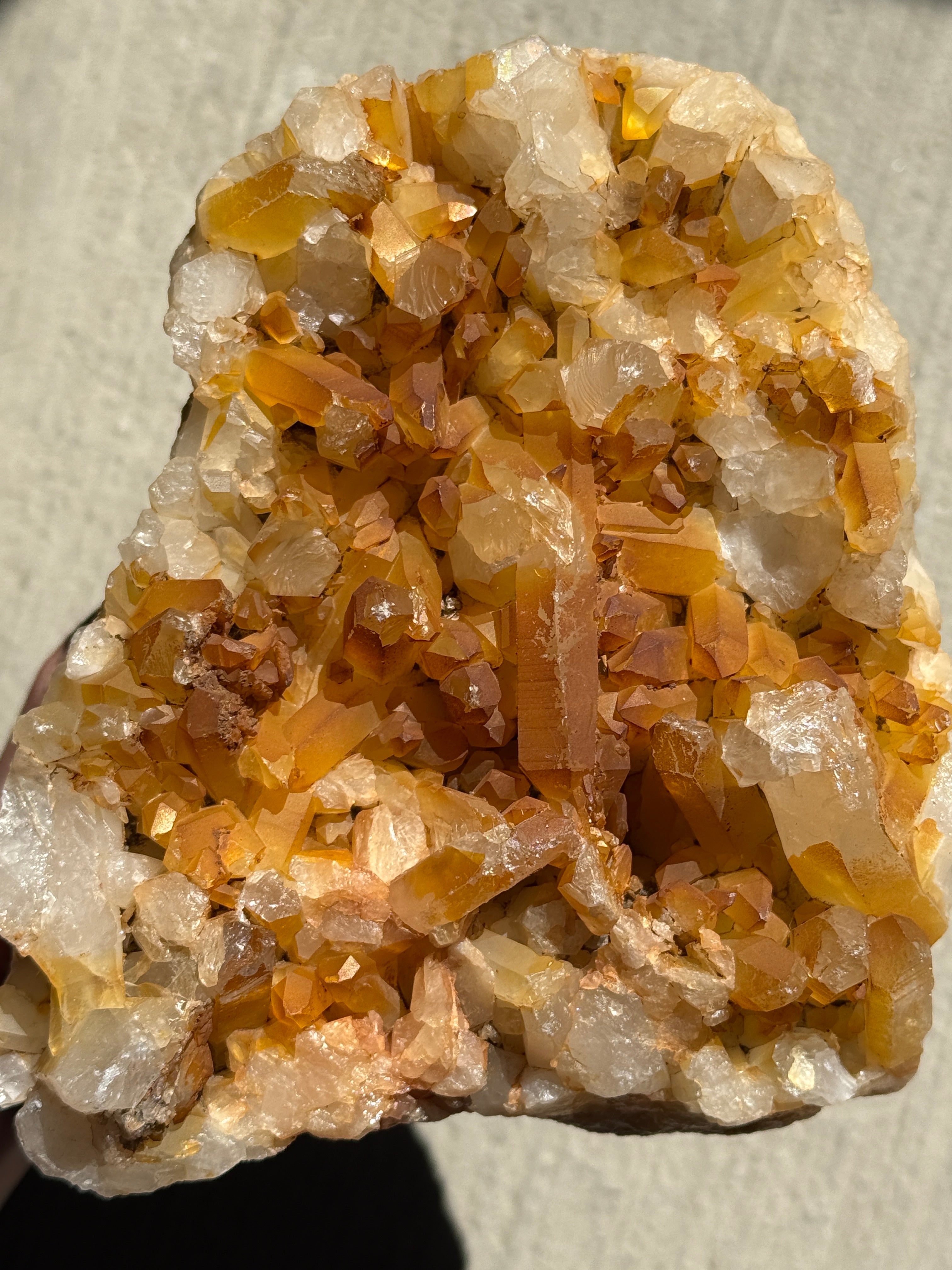 A cluster of raw mineral crystals featuring deep amber-colored points and a mix of translucent white points . The specimen has a jagged, irregular shape with numerous sharp, multifaceted terminations protruding from a central rocky base.