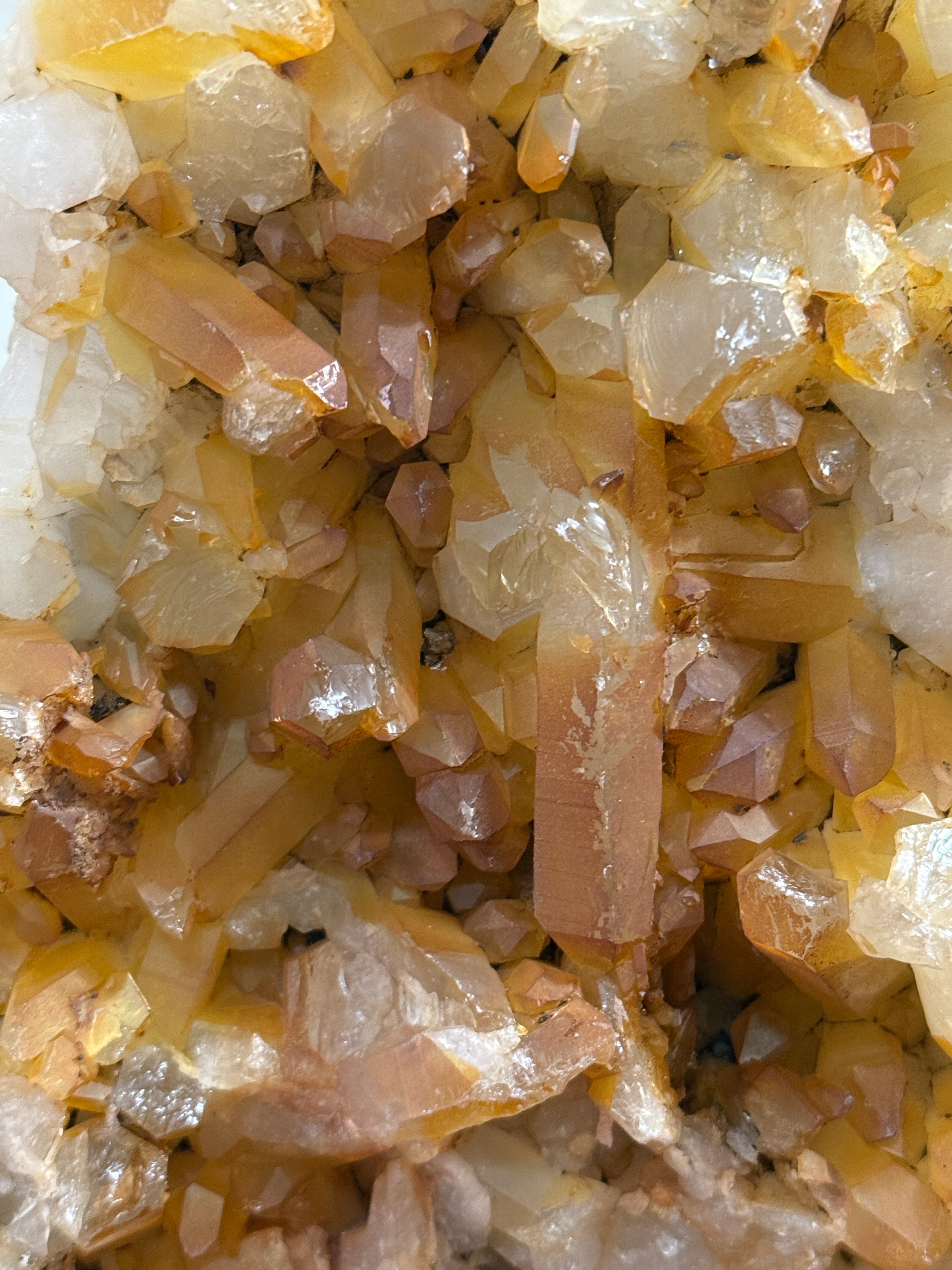 Close-up of a crystal cluster with translucent pale yellow, amber, and off-white mineral crystals filling the frame.